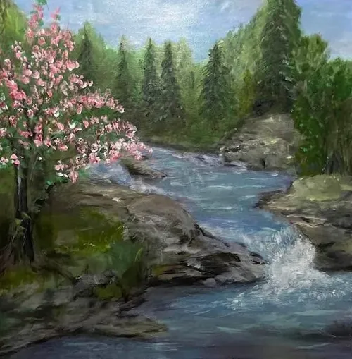 A river crashing on the rocks beside a cherry tree